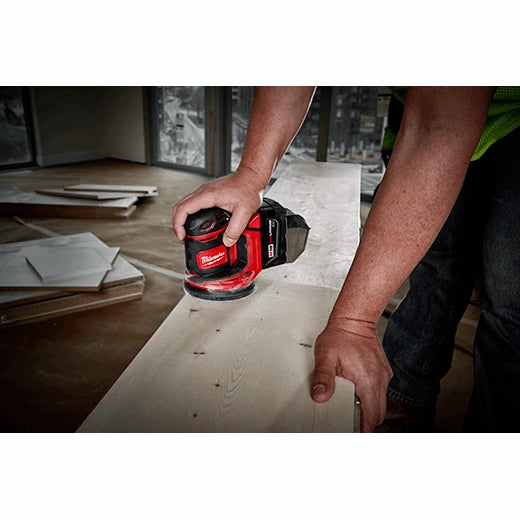 Lijadora Milwaukee M18 en acción lijando superficie de madera natural